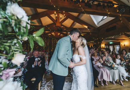 Bride and groom exchanging vows during their wedding ceremony at The King Arthur Hotel in Gower, South Wales. The stone courtyard and coastal surroundings provide a romantic backdrop for natural, cinematic wedding photography.