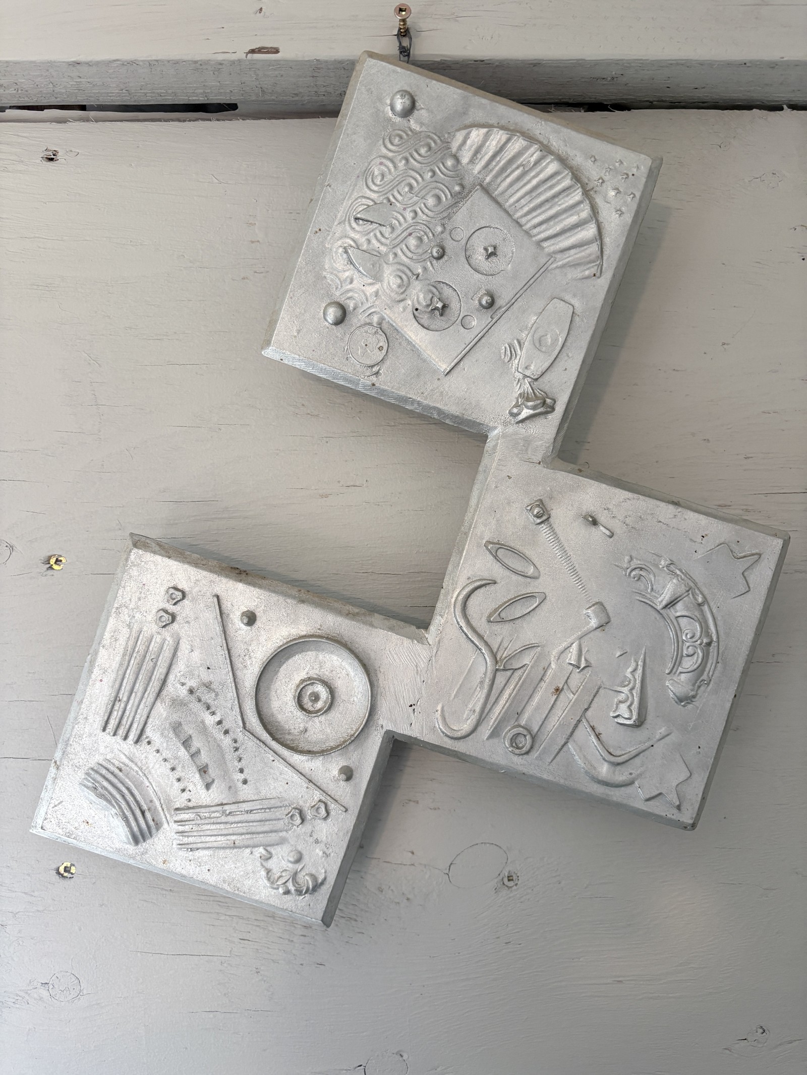 Abstract mixed media wall sculpture titled 'Geometica' by Saskatoon metal artist Rik (Rick Luczka). This unique piece features two joined square steel panels with raised, textured geometric swirls and organic patterns mounted on a light wood base. Perfect for modern home or office wall decor; handcrafted in Saskatchewan.