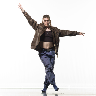 Ash poses in a leather jacket and baggy pants.