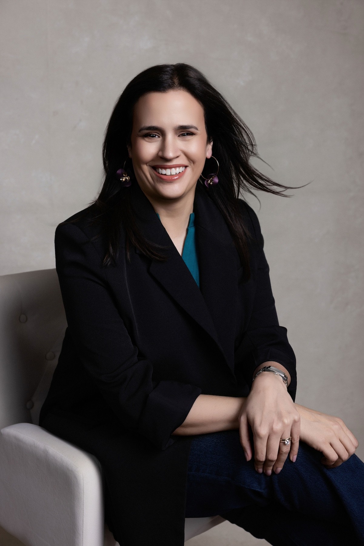 Alison Migneault, Founder of Kind Strategy sits in a chair, smiling at the camera.