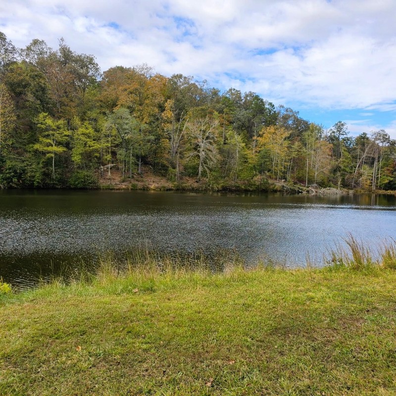 Beautiful autumn view of the 4-acre stocked lake with colorful fall foliage reflecting in the calm waters, perfect for peaceful reflection and fishing