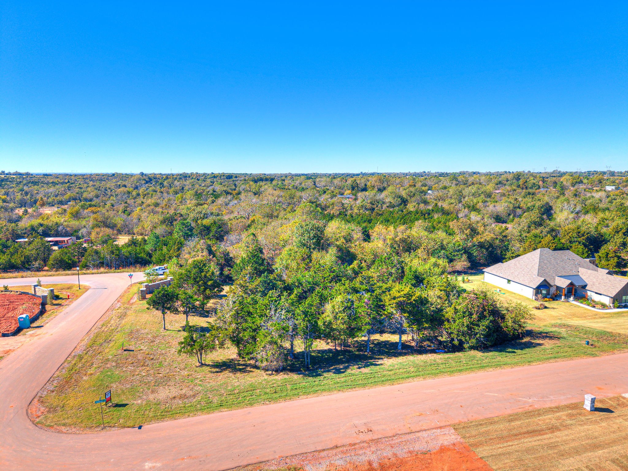 Front view of Lot 1 in Highland Estates, Mustang Oklahoma showing spacious tree-lined acreage ready for a custom home build.