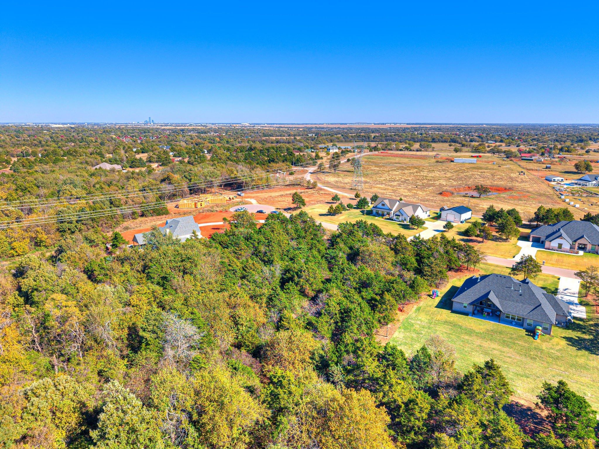 Aerial photo of Lot 8 A in Highland Estates Mustang Oklahoma showing large tree-covered acreage and neighboring custom homes.