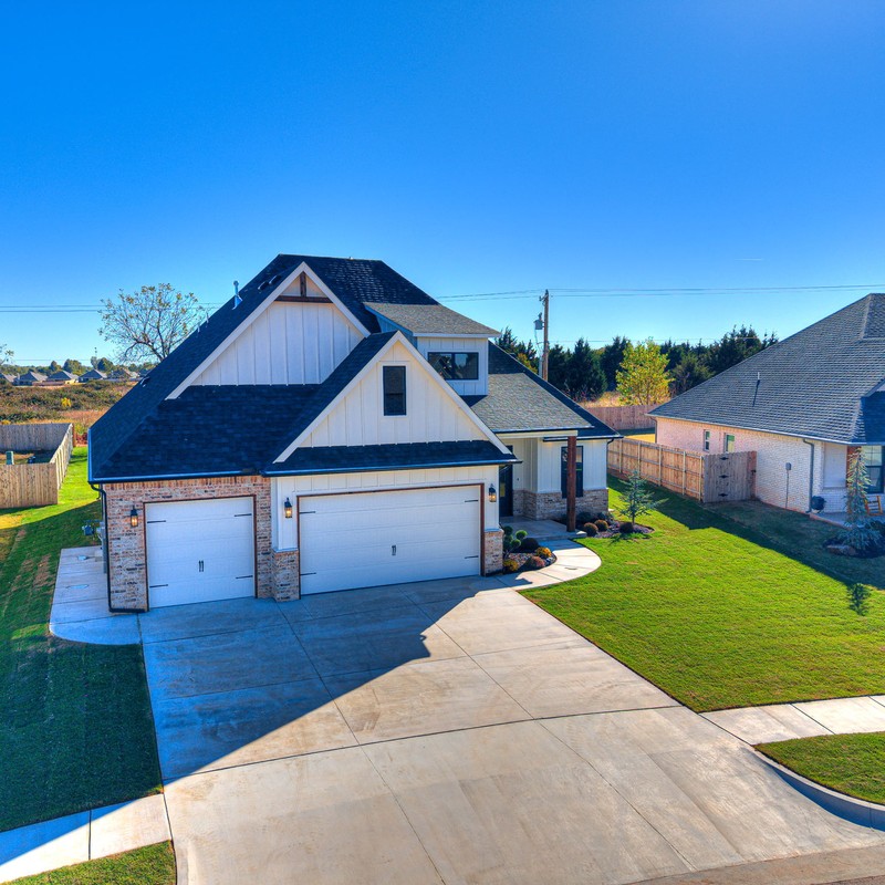 Aerial angle showing the Mustang OK custom home on SW 51st Street with surrounding neighborhood and wide driveway.