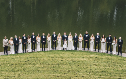 Bride, groom, and bridal party captured laughing together at Canada Lakes, Vale of Glamorgan, South Wales. The lush outdoor surroundings and reflective water provide a picturesque backdrop for natural and joyful wedding photography.