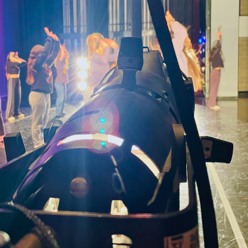 A stage light lights Jones College Prep students standing on stage.