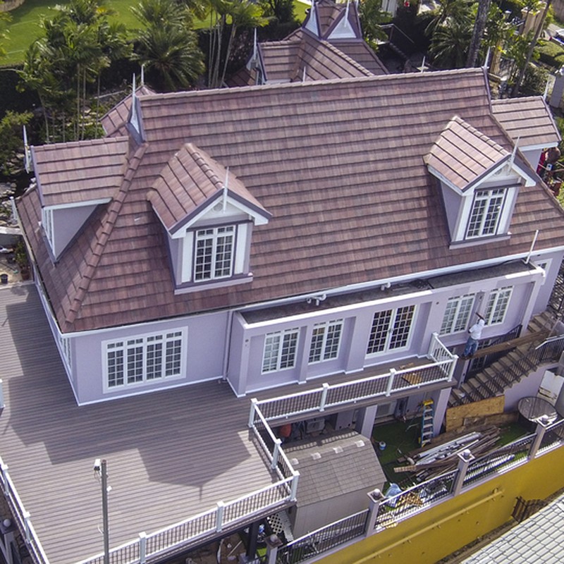 Aerial shot showing newly installed decking and railings extending the upper level of a large, lavender-coloured, 2-storey house.