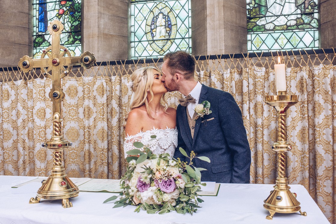 First kiss on the wedding day during a church wedding in Usk, Wales
