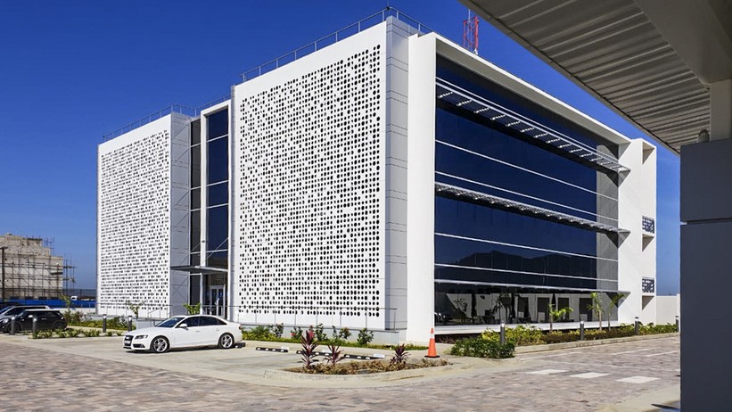 Oblique angle shot showing the newly installed large 2-panel fretwork covering the front of a 3-story commercial building, coloured in white.