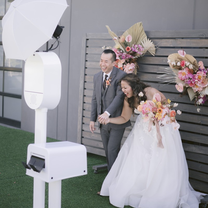 Friends and family gather for a joyful group shot in front of a green leaf backdrop using the VA Shoreline Events photo booth at a Norfolk wedding. Captured with DSLR lighting and instant sharing.