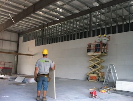 gypsum board installation being done by 3 PatchBoyz technician in toronto. 2 on a lift and one on the ground.