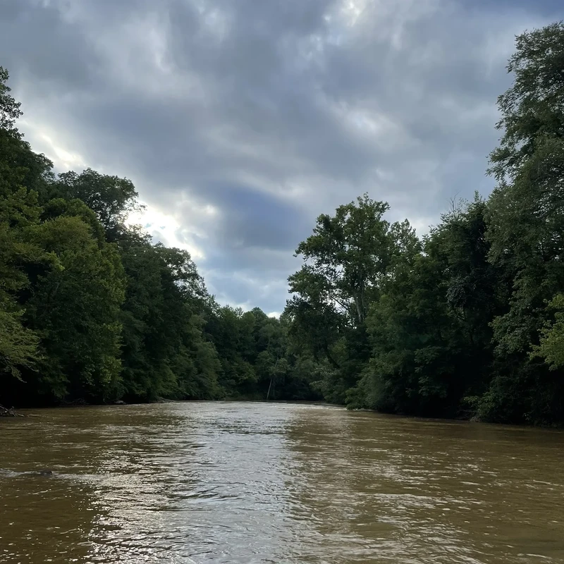 The historic Pacolet River flowing through the property under dramatic cloud formations, showcasing the natural beauty of the riverfront access