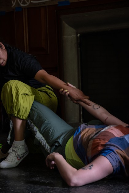 Performance from FOLK. A dancer lying on their back reaches and clasps hands with a dancer crouched over them.