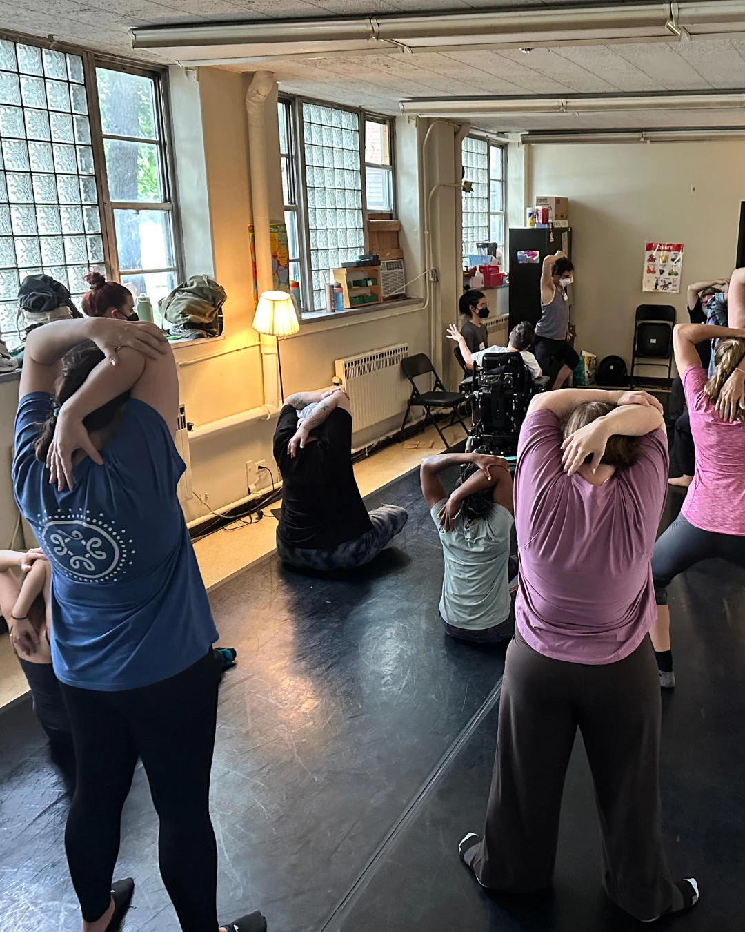 Full Radius Integrated Dance class sits and stands performing a triceps stretch.