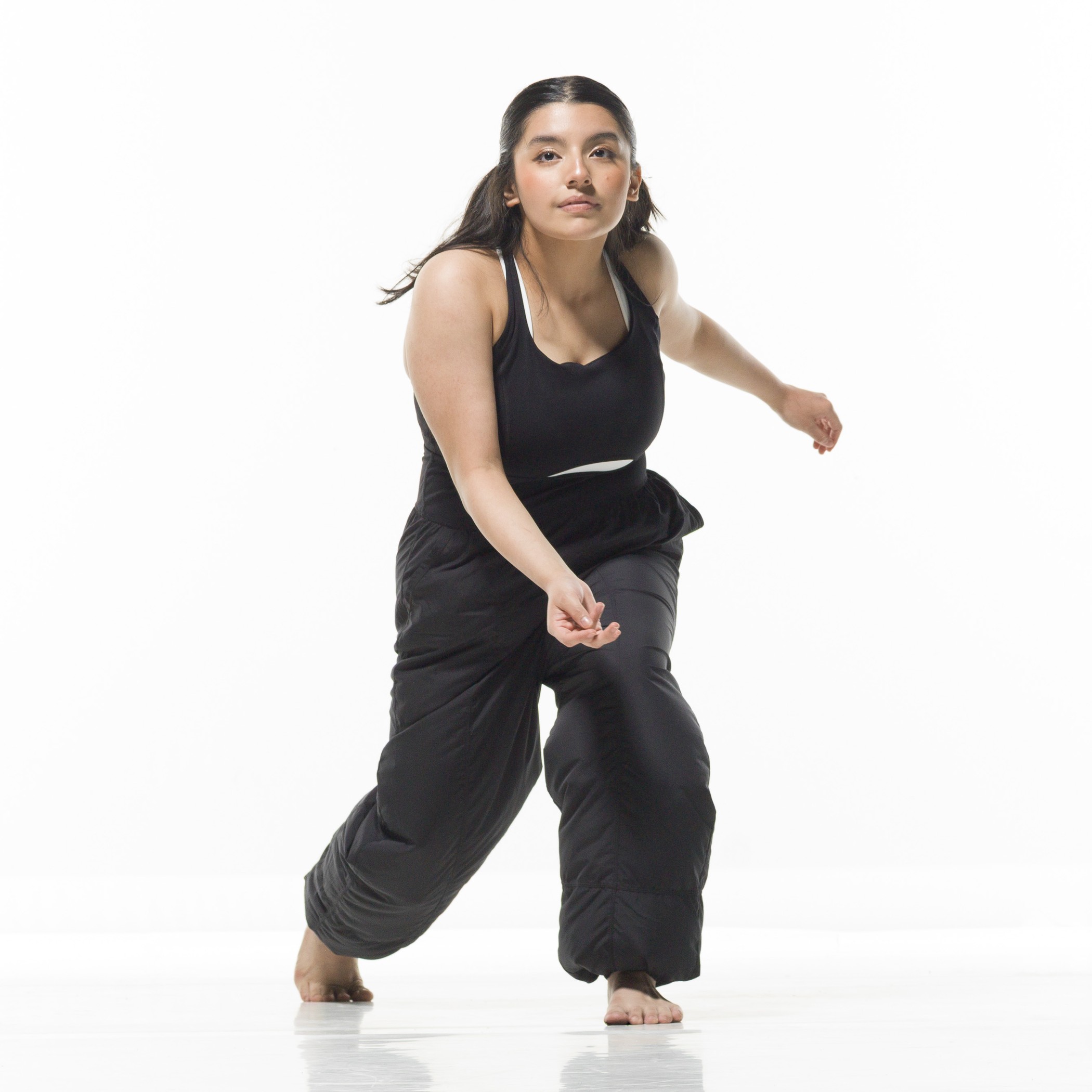 Emily moves in motion in a black tank top and pants against a white backdrop.