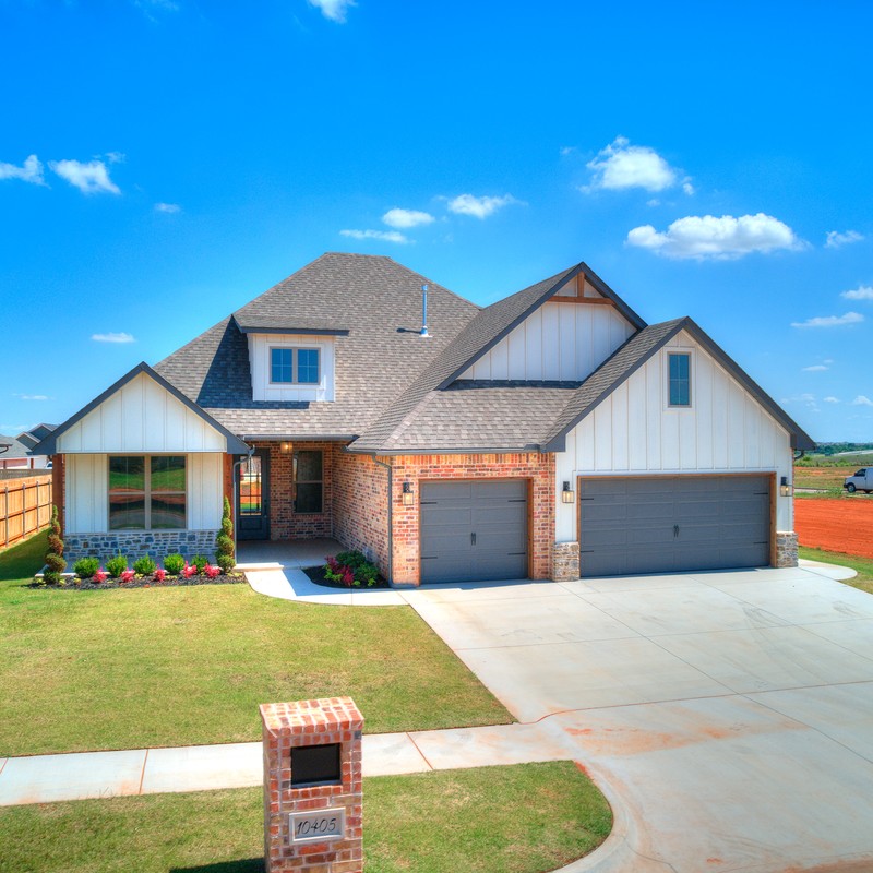 Front exterior of custom home at 10405 SW 50th St, Mustang OK showing garage and entryway.
