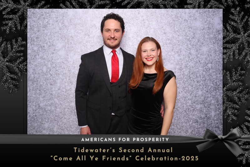 Two guests dressed in formal attire pose together in front of a silver textured photo booth backdrop at the Americans for Prosperity Tidewater's Second Annual 