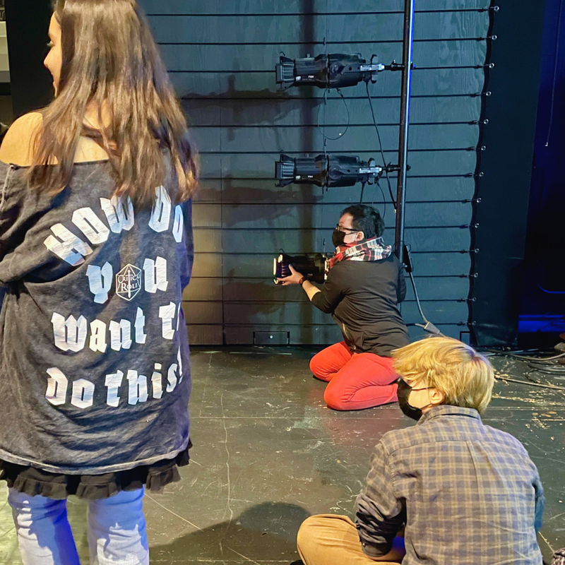 Rachel Damon operates a stage light. Jones College Prep students watch.