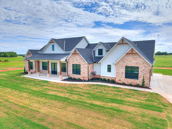 The Fernandez Custom Home features a 3,300 sq. ft. layout with stone and siding exterior, large windows, and a metal roof. Built by Merryfield Homes on a five-acre property in Mustang, OK, the home includes four bedrooms, a game room, and elegant interior finishes that showcase expert craftsmanship.