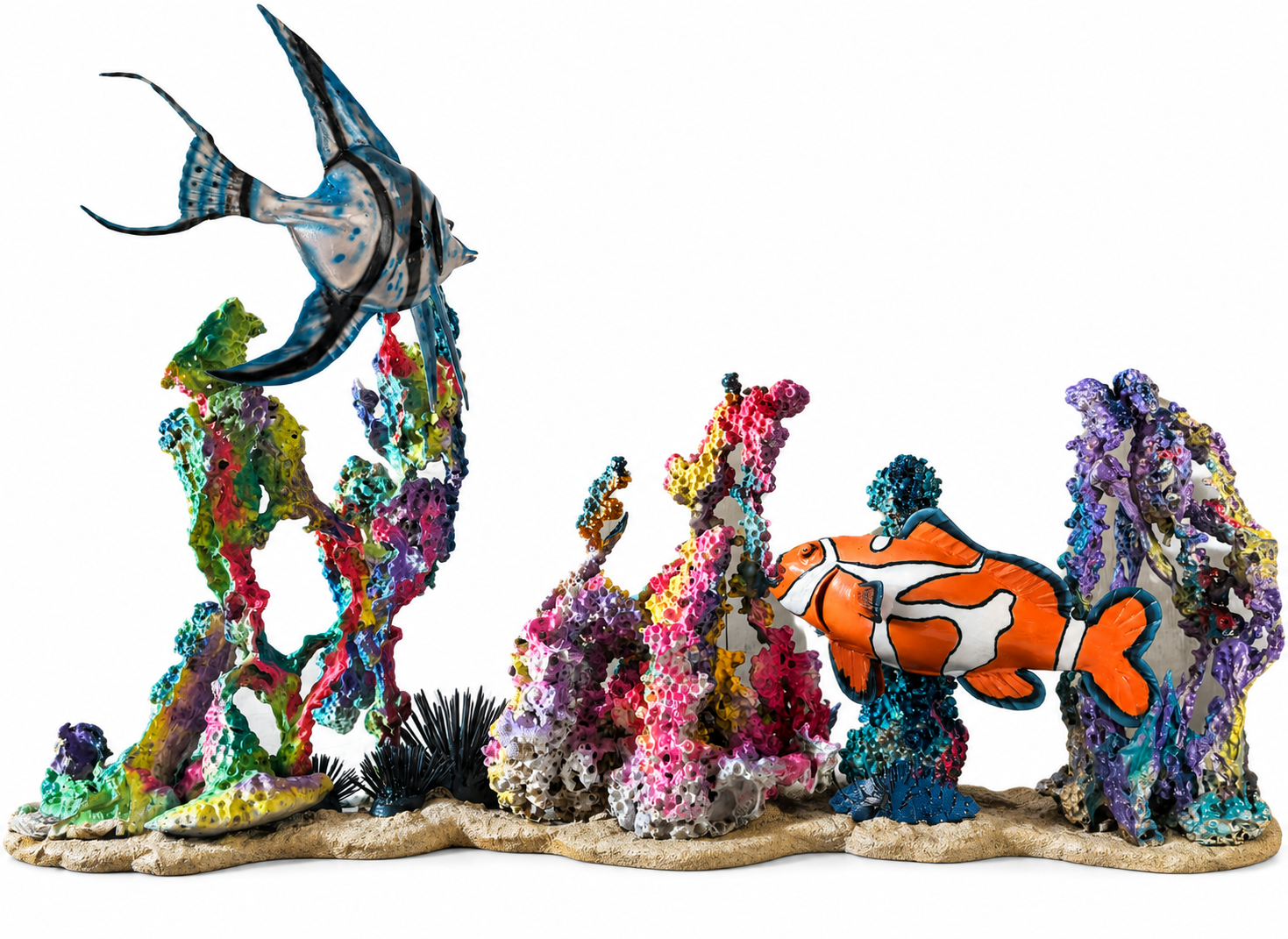 A sculpted underwater scene featuring a blue angelfish, clownfish, colorful coral, and a black sea urchin on a sandy base, displayed against a plain light wooden background.