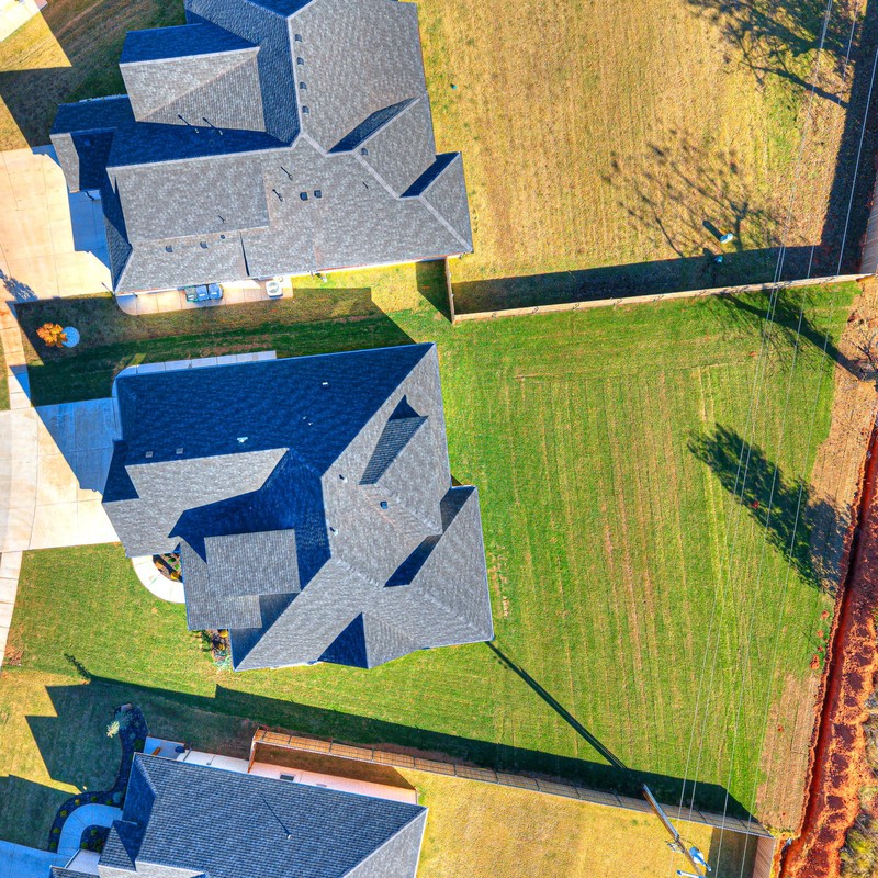 Top-down aerial showing the large backyard lot and full roofline of the 10408 SW 51st Street custom home in Mustang Oklahoma.