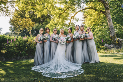 bridesmaids photographed outside The King Arthur Hotel on the Gower Peninsula, South Wales. The warm golden light highlights the rustic stone architecture and coastal surroundings, creating cinematic wedding photography.