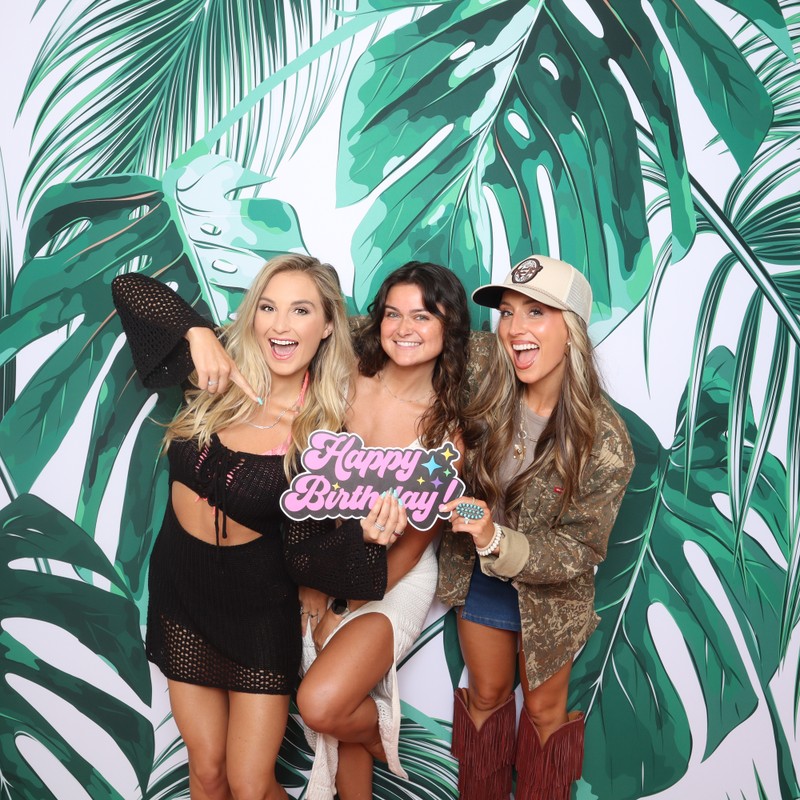 Birthday photo booth collage featuring friends posing together in front of a tropical palm leaf backdrop, framed with beach-inspired graphics and 