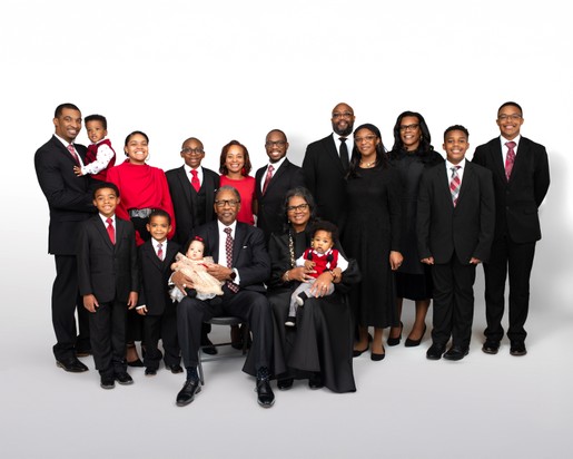 Aerial view of a large wooded property with dense green forest surrounding open grassy fields, winding dirt paths, and a small building nestled among the trees.”