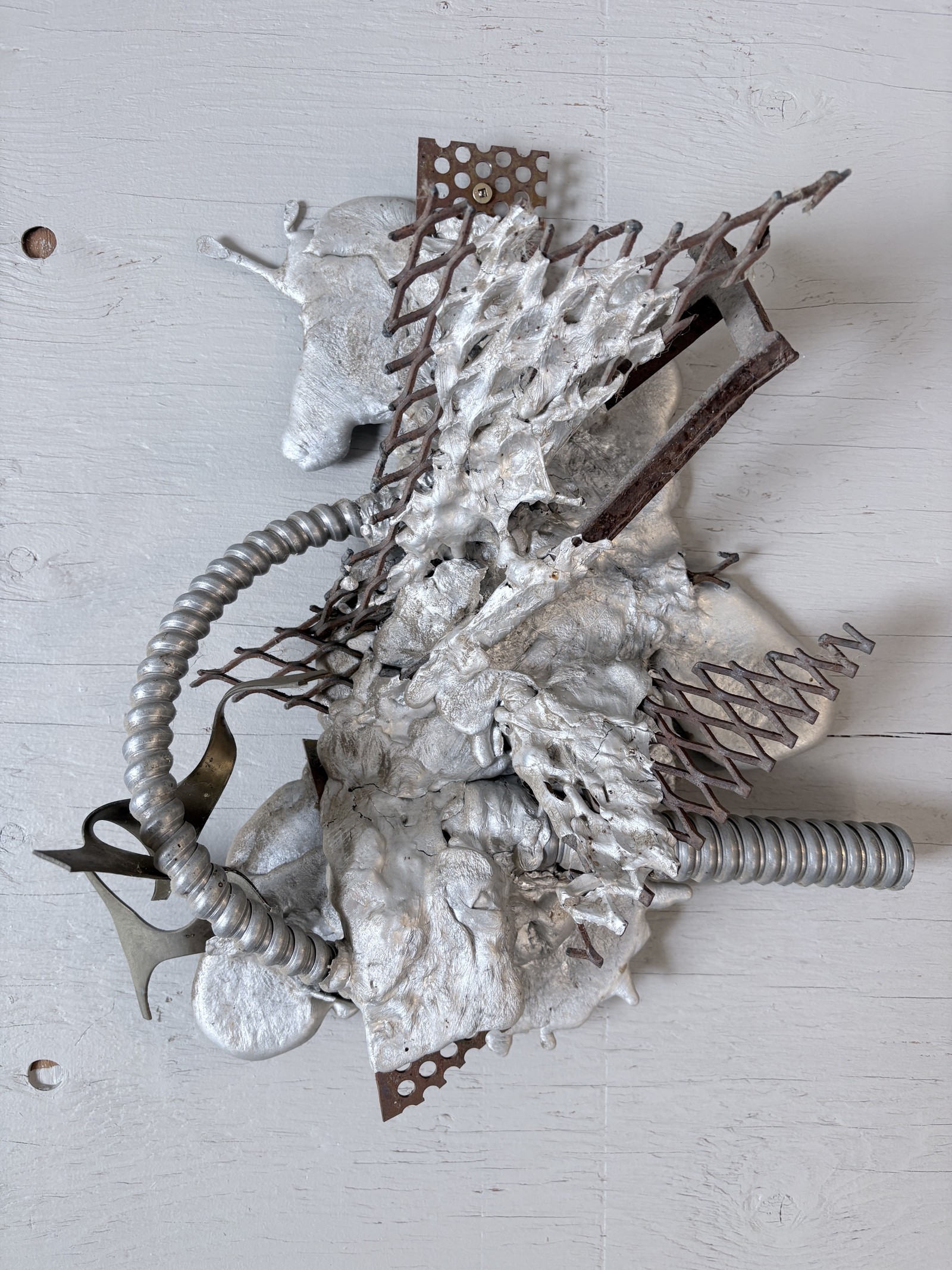 Industrial mixed-media wall sculpture titled 'No Weld Study' by Saskatoon metal artist Rik (Rick Luczka). This abstract composition features twisted metal mesh and corrugated tubing fused within a molten aluminum matrix on a light wood base. A unique example of experimental metal fabrication and custom metal art from Saskatchewan, perfect for modern or industrial interior decor.