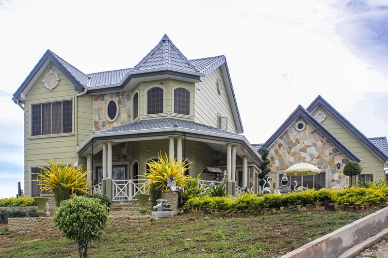Front angle shot of a newly built 2-story house with green walls and a grey roof.