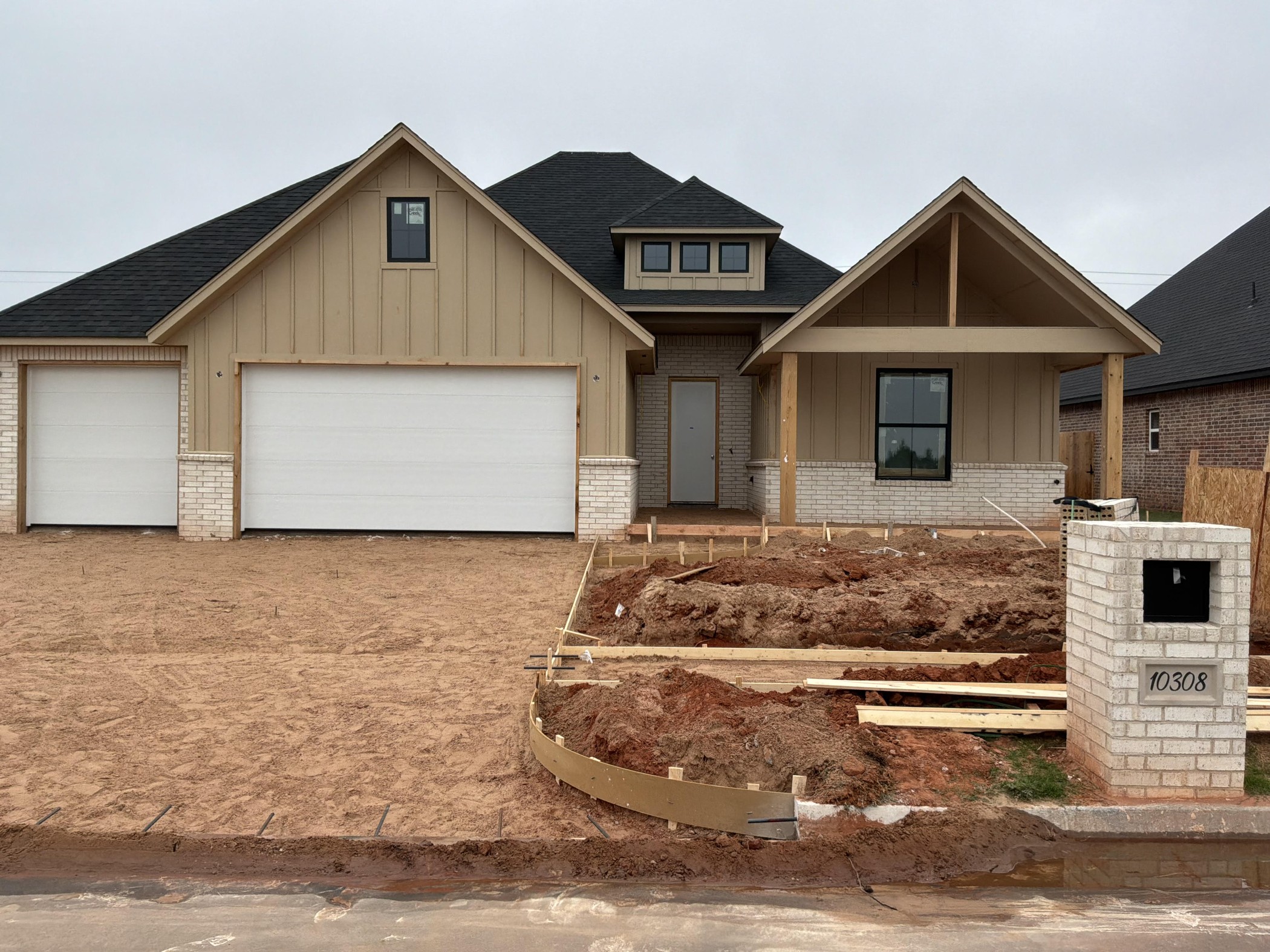 Custom home under construction in Mustang, Oklahoma by Merryfield Homes featuring a modern farmhouse design, three-car garage, and front elevation view.