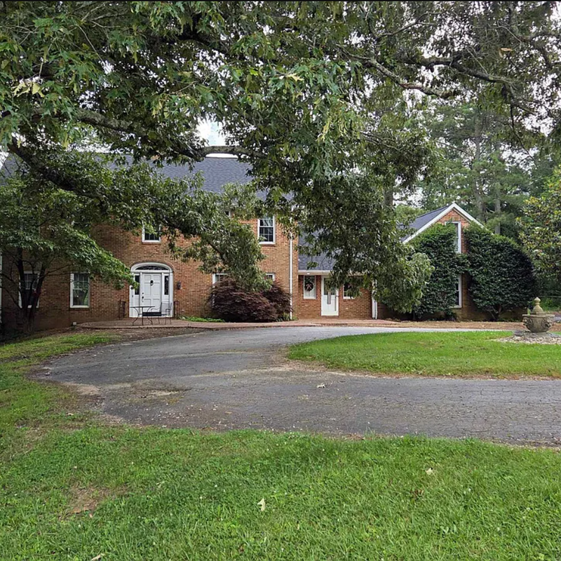 Front view of the beautiful 1978 brick home that serves as the heart of the National Campus, surrounded by mature shade trees