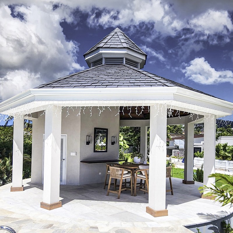 Frontal shot showing a newly built gazebo, with white and light grey coloured walls and pillars, and darker grey coloured roofing.